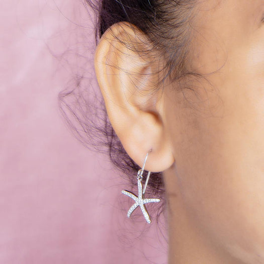 The picture shows a model wearing a 925 sterling silver pavé white gold vermeil sea star hook earring.