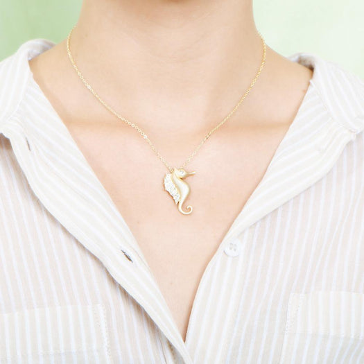 The picture shows a model wearing a 925 sterling silver, yellow gold vermeil, pavé seahorse pendant with topaz.