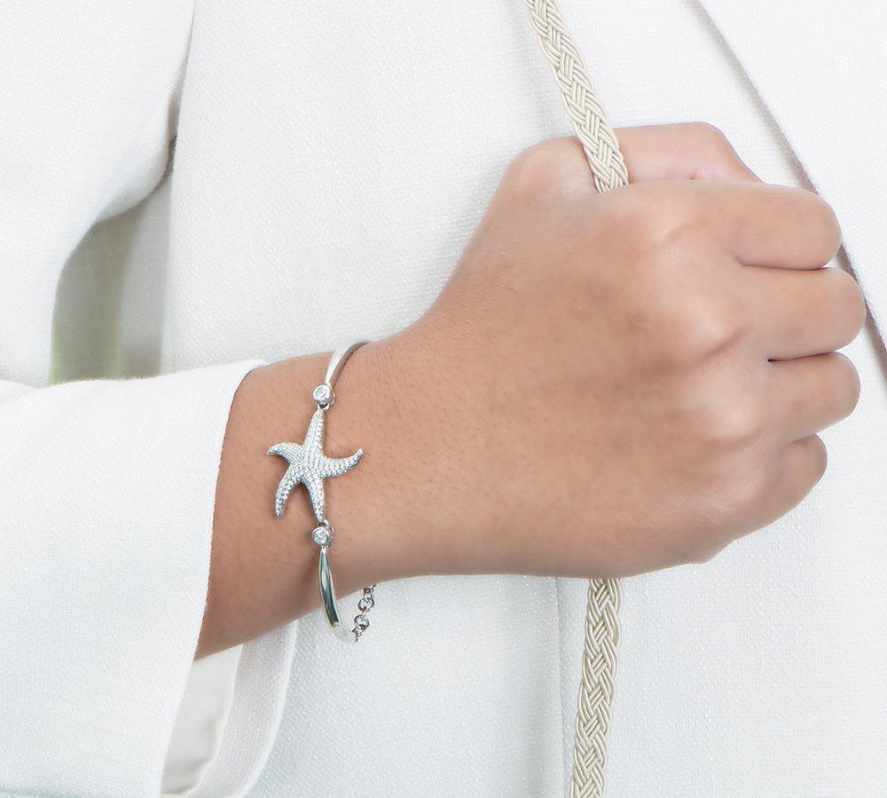 The picture shows a model wearing a 925 sterling silver starfish chain bracelet with topaz.