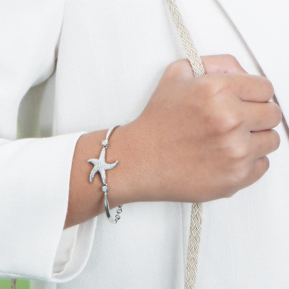 The picture shows a model wearing a 925 sterling silver starfish chain bracelet with topaz.