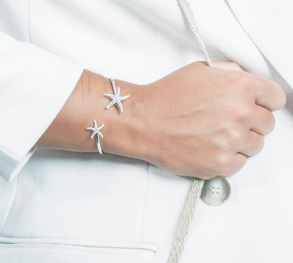 The picture shows a model wearing a 925 sterling silver two starfish bangle with topaz.