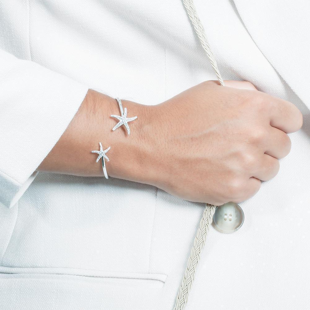The picture shows a model wearing a 925 sterling silver two starfish bangle with topaz.