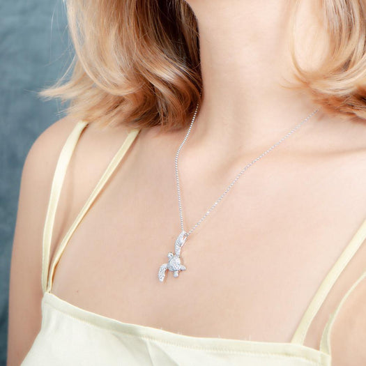 The picture shows a model wearing a 925 sterling silver, white gold vermeil, sea turtle pendant with topaz.