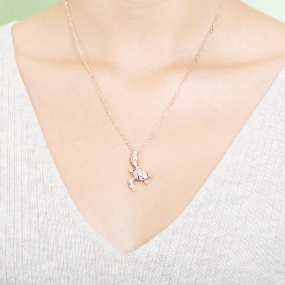 The picture shows a model wearing a 925 sterling silver, rose gold vermeil, sea turtle pendant with topaz.