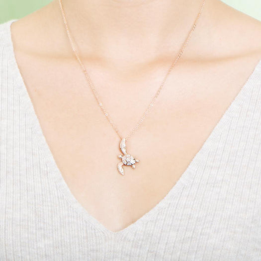 The picture shows a model wearing a 925 sterling silver, rose gold vermeil, sea turtle pendant with topaz.