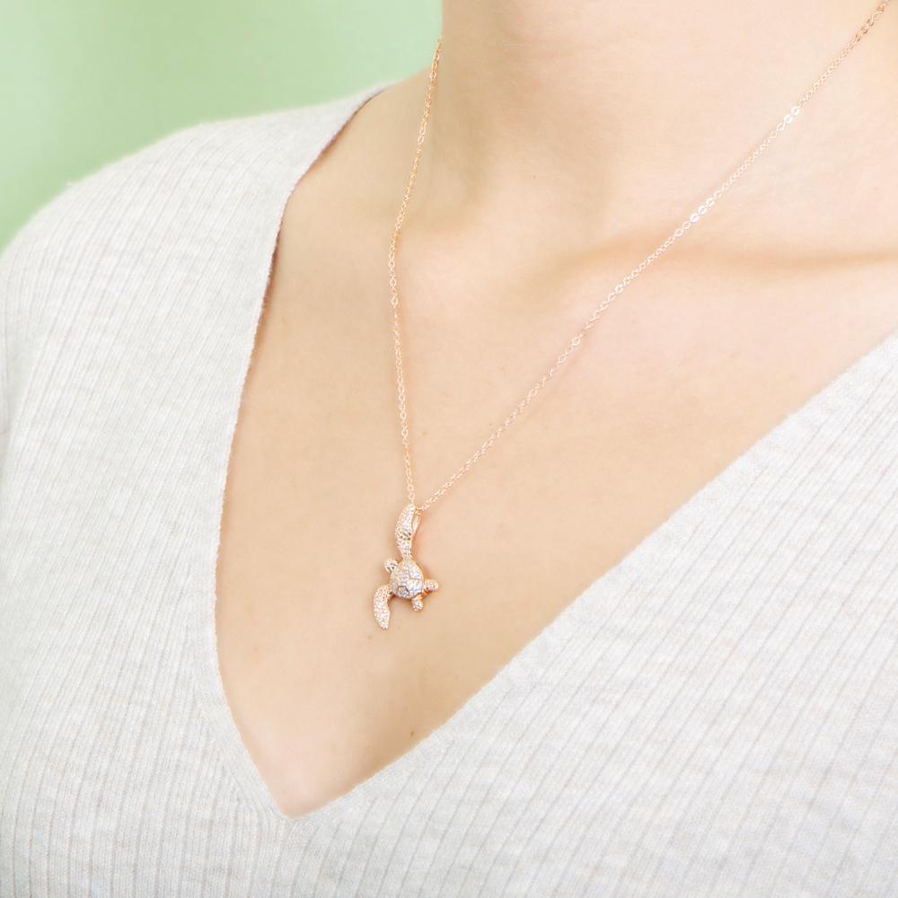 The picture shows a model wearing a 925 sterling silver, yellow gold vermeil, sea turtle pendant with topaz.