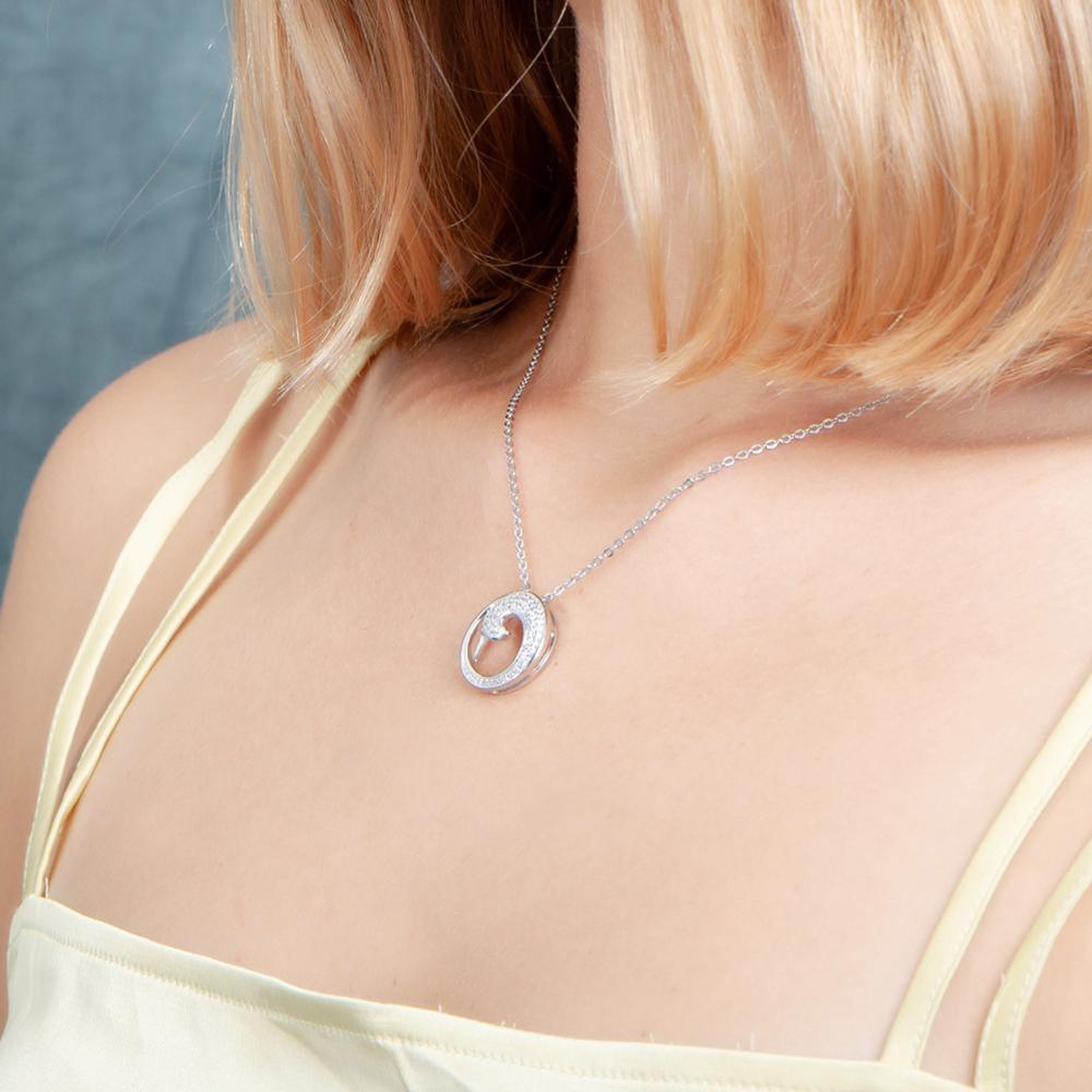 The photo is shows a model wearing a sterling silver pavé wave pendant with topaz.
