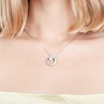 The photo is shows a model wearing a sterling silver pavé wave pendant with topaz.