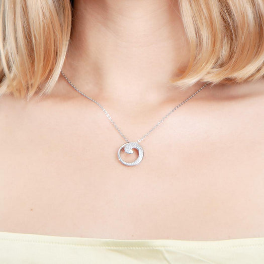 The photo is shows a model wearing a sterling silver pavé wave pendant with topaz.