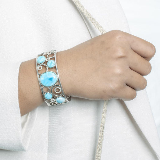 The picture shows a model wearing a 925 sterling silver bangle with five larimar gemstones and topaz.