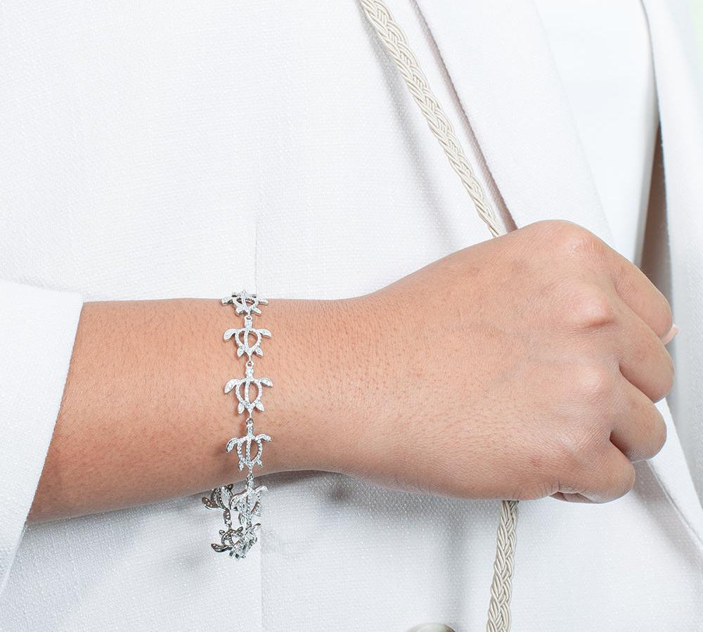 The photo shows a model wearing a 925 sterling silver white gold-plated Polynesian sea turtle bracelet with topaz.