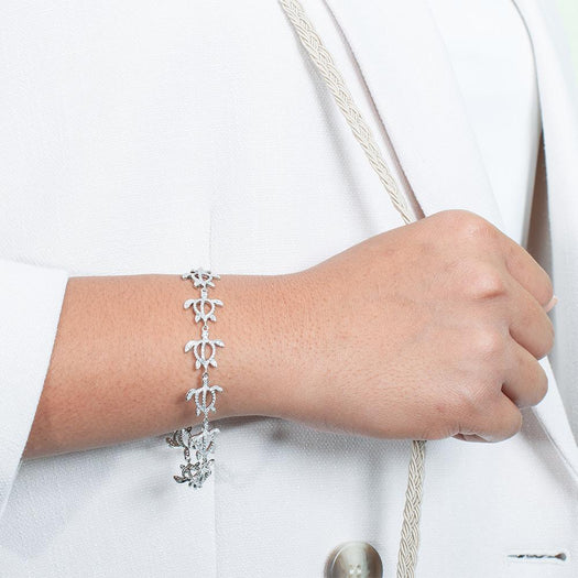 The photo shows a model wearing a 925 sterling silver white gold-plated Polynesian sea turtle bracelet with topaz.