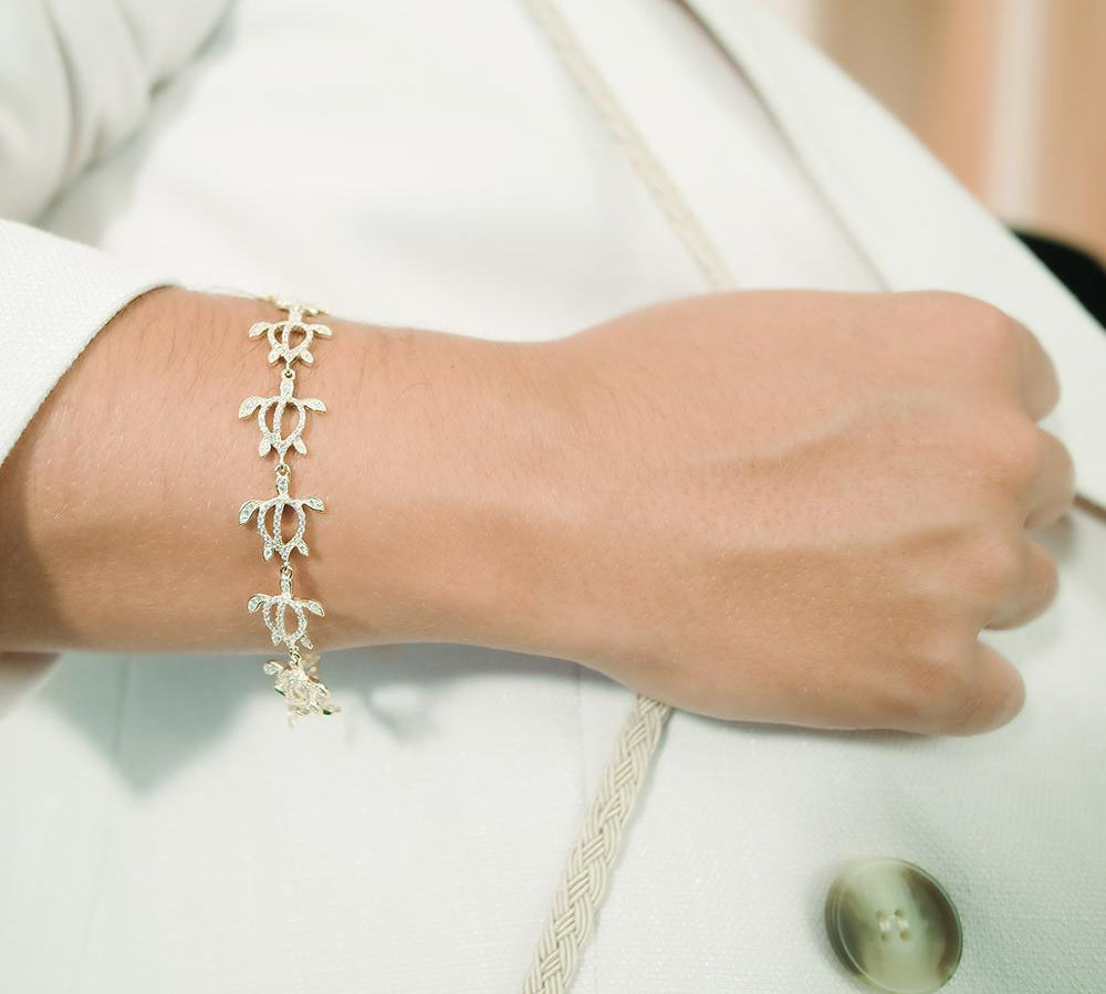 The photo shows a model wearing a 925 sterling silver yellow gold-plated Polynesian sea turtle bracelet with topaz.