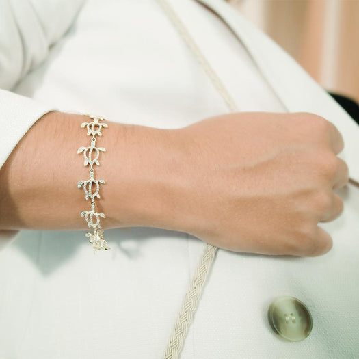 The photo shows a model wearing a 925 sterling silver yellow gold-plated Polynesian sea turtle bracelet with topaz.