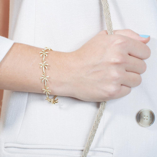 In this photo there is a model wearing a yellow gold plated palm tree bracelet with topaz gemstones.