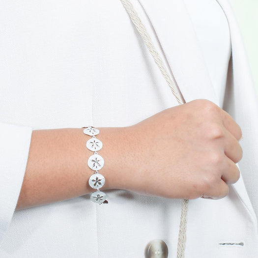The picture shows a model wearing a white gold sand dollar bracelet