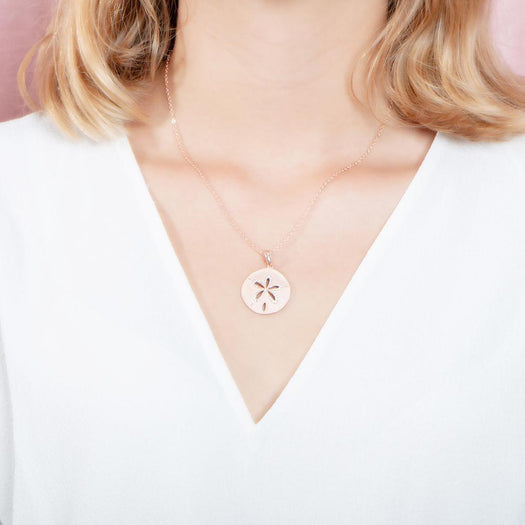 The picture shows a model wearing a rose gold sand dollar cut out pendant.
