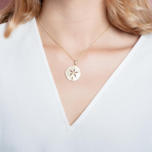 The picture shows a model wearing a yellow gold sand dollar cut out pendant.