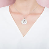 The picture shows a model wearing a white gold sand dollar cut out pendant.