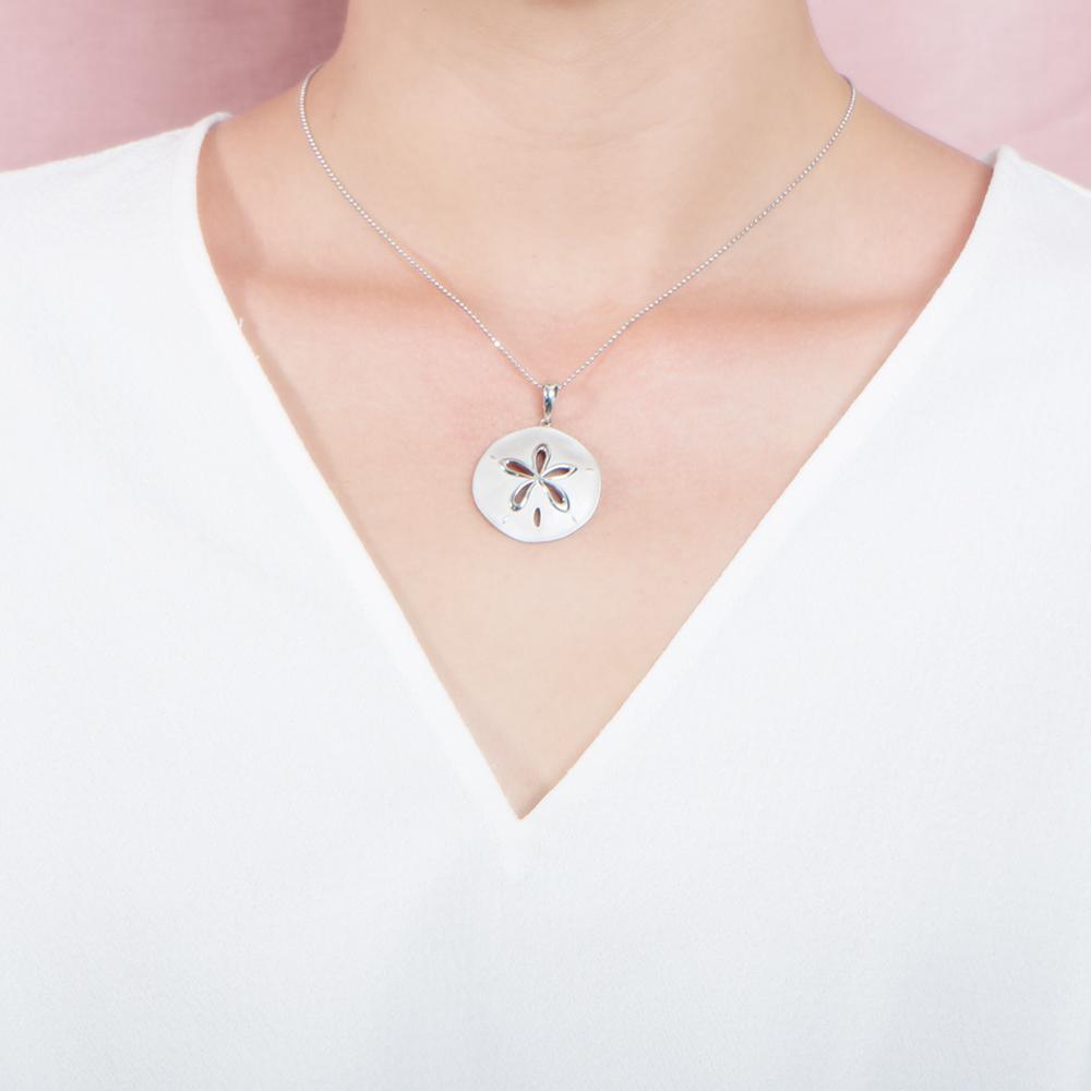 The picture shows a model wearing a white gold sand dollar cut out pendant.