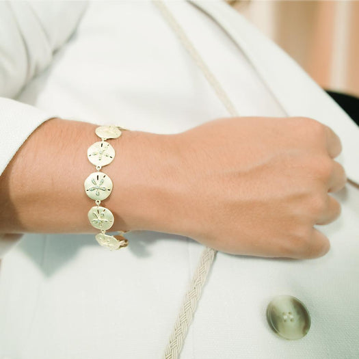 The picture shows a model wearing a yellow gold sand dollar bracelet with topaz.