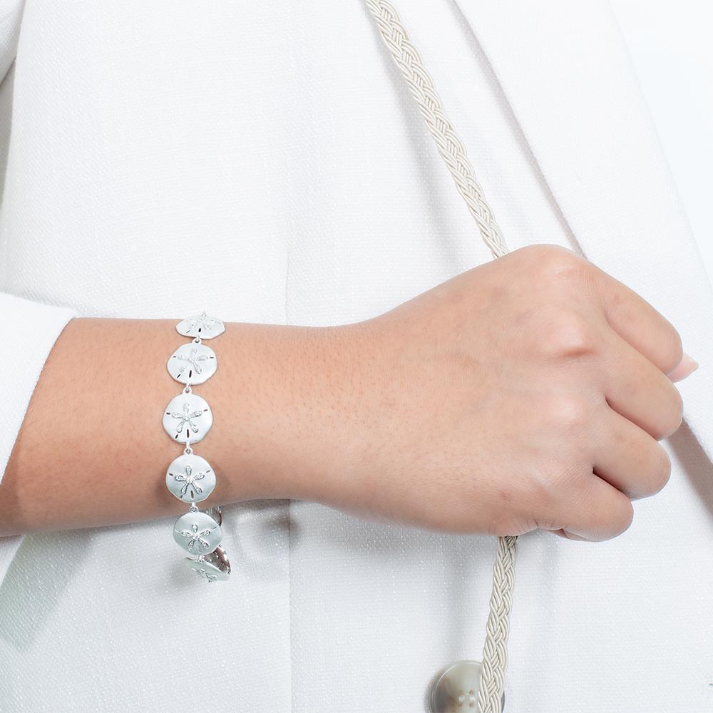 The picture shows a model wearing a white gold sand dollar bracelet with topaz.