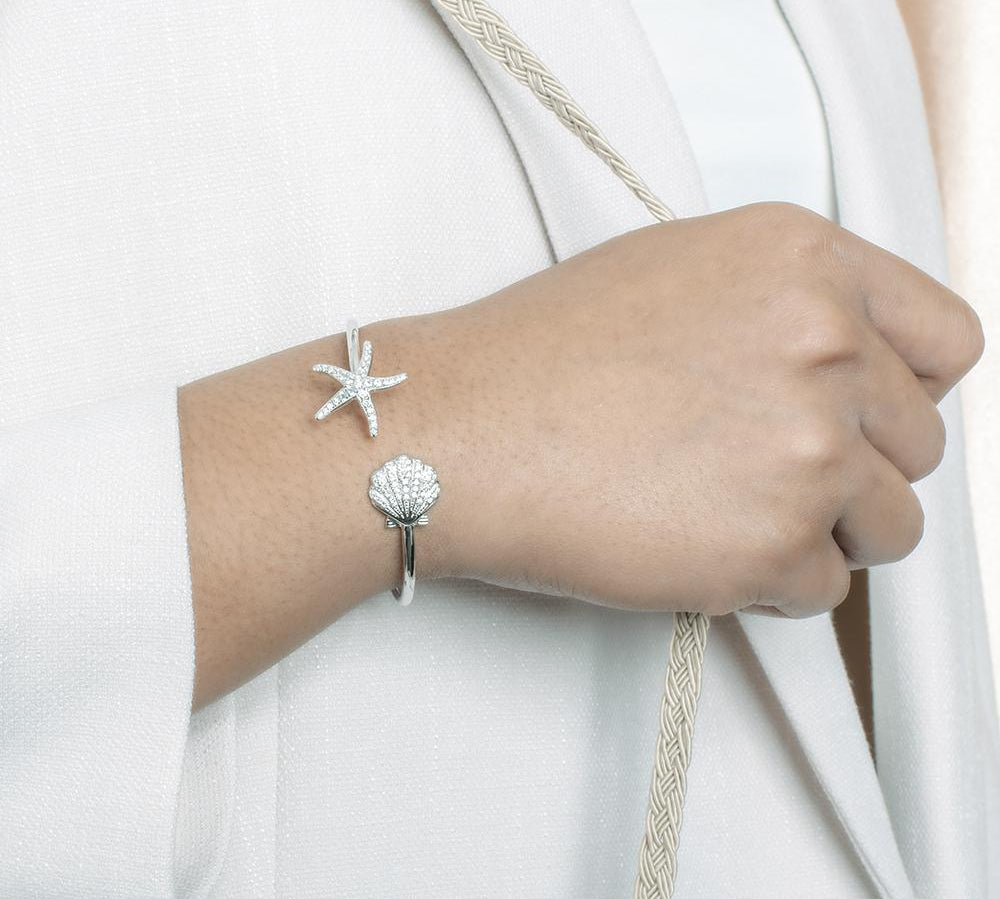 The picture shows a model wearing a 925 sterling silver starfish and oyster bangle with topaz.