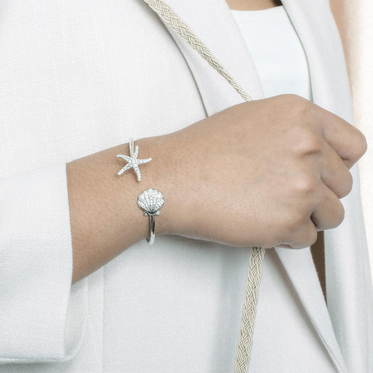 The picture shows a model wearing a 925 sterling silver starfish and oyster bangle with topaz.