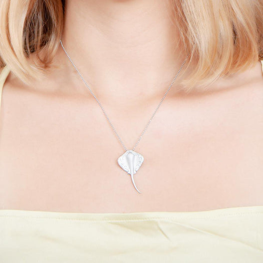  The picture shows a model wearing a white gold manta ray pendant with topaz.