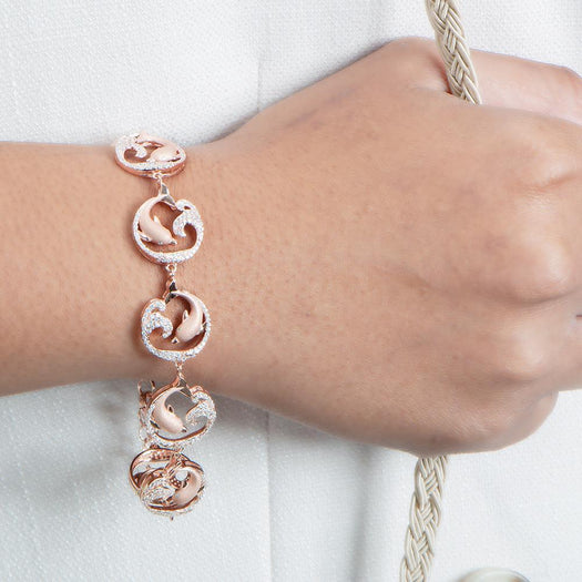 The picture shows a model wearing a rose gold dolphin and wave bracelet with topaz.