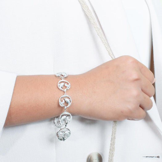 The picture shows a model wearing a white gold dolphin and wave bracelet with topaz.