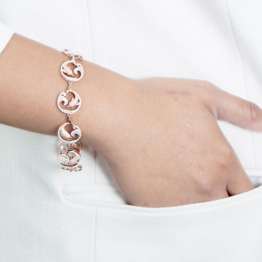The picture shows a model wearing a rose gold dolphin and wave bracelet with topaz.